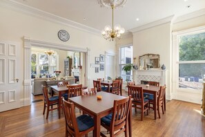 Una sala da pranzo con tavoli e sedie in legno, un lampadario e un orologio appeso al muro.