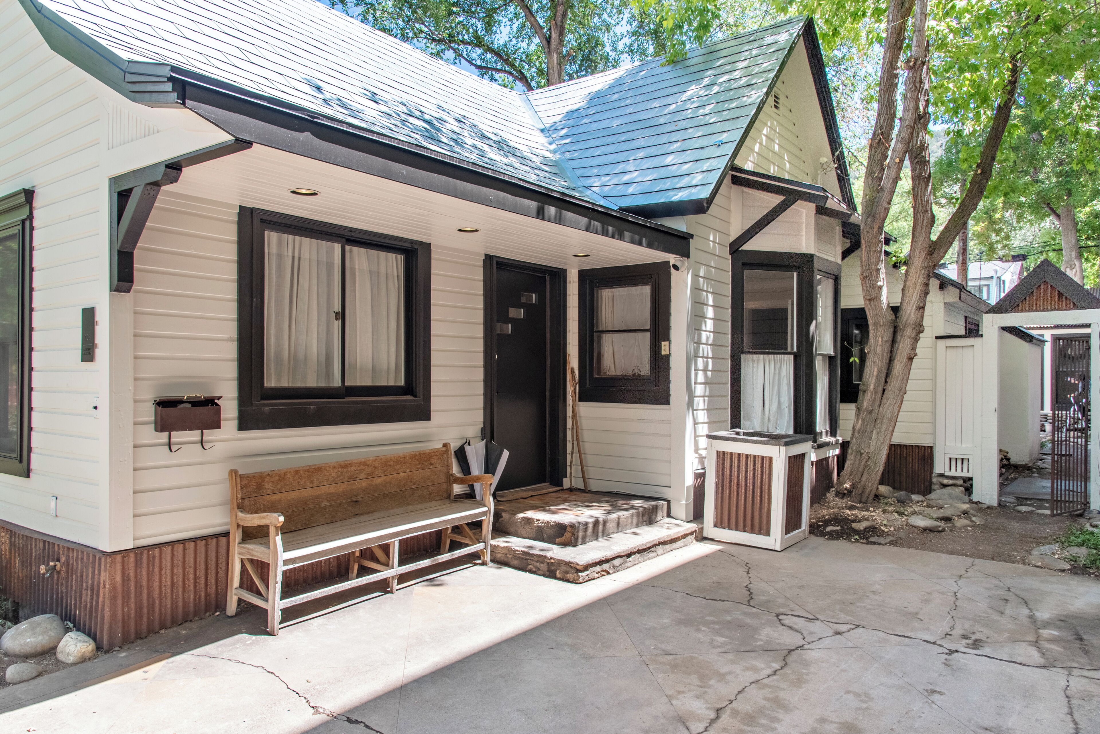 A single-story house with a porch, a bench, and a small table.
