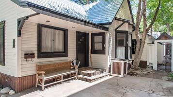 A single-story house with a porch, a bench, and a small table.