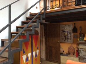 A staircase with a geometric design, a wooden door, and a wall with a poster and decorative items.