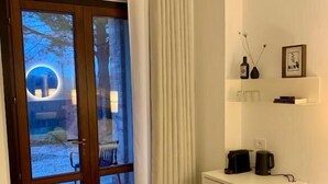 Une chambre moderne dotée d’une porte-fenêtre coulissante, d’une console blanche et d’une petite étagère ornée d’objets décoratifs.