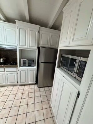 A kitchen with white cabinets, a stainless steel refrigerator, and a microwave. - Mid Century Garden View Home Parking (San Mateo)
