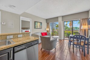 A modern kitchen with granite countertops, a dishwasher, and a dining area with a table and chairs. - Scenic Lakeview Condo w Balcony and Resort Pools (Orlando)