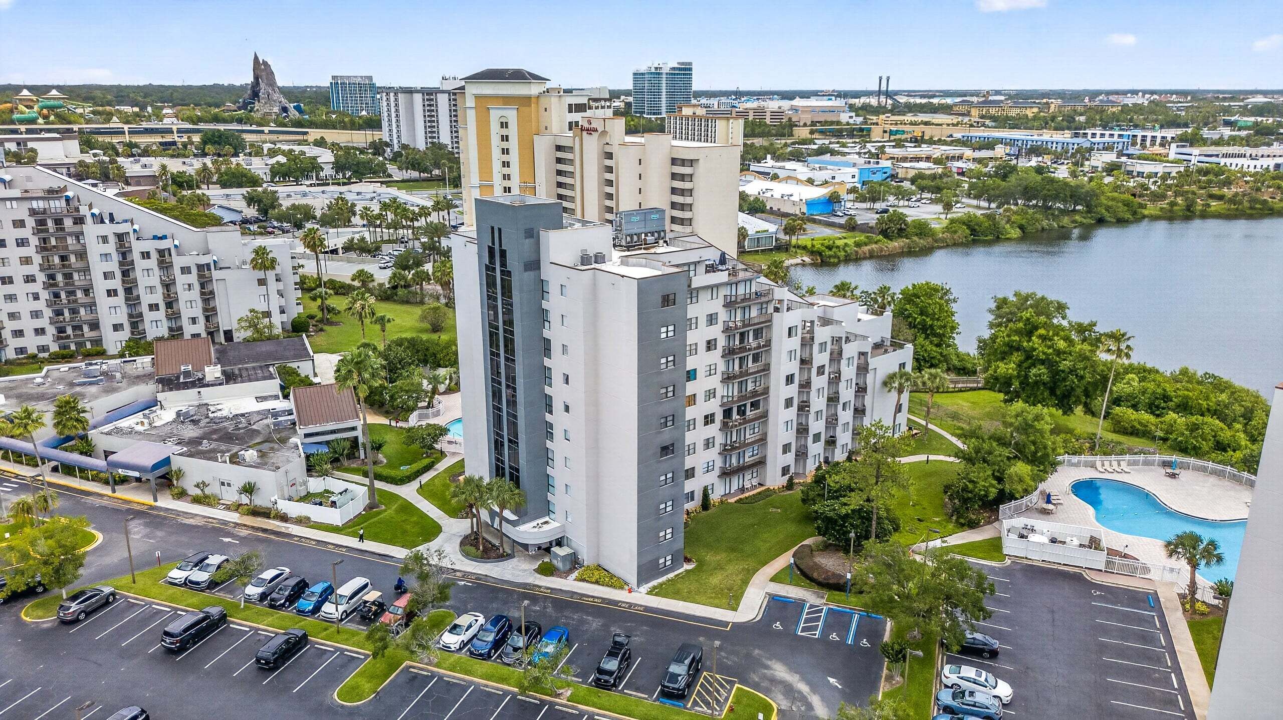 A high-rise hotel with multiple floors, a swimming pool, and a parking lot.