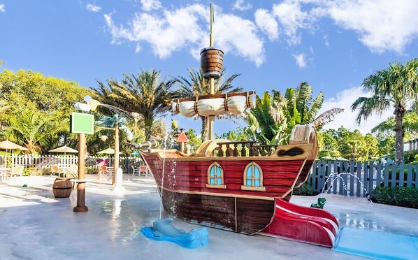 Eine wasserrutsche im Piratenschiff-Design mit Holzdeck, Fenstern und einer Flagge.