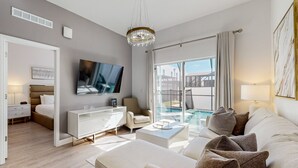 Ein modernes Hotelzimmer mit einem großen Bett, einem Fernseher, einem Sofa, einem Couchtisch und Blick auf einen Swimmingpool.