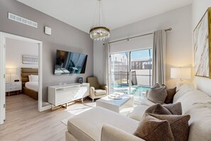 A modern hotel room with a large bed, a TV, a sofa, a coffee table, and a view of a swimming pool. - Two-story Townhouse With Private Pool, Screened Lanai, Washer/dryer (Davenport)