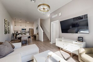 A modern living room with a white sofa, a coffee table, a TV, and a staircase leading to the kitchen. - Two-story Townhouse With Private Pool, Screened Lanai, Washer/dryer (Davenport)