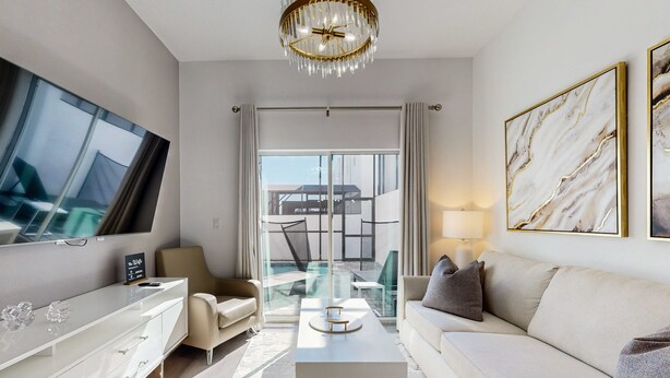 Ein modernes Hotelzimmer mit Flachbildfernseher, einer Couch, einem Couchtisch und einem Glastisch.
