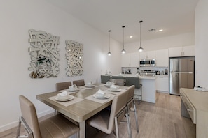 A modern kitchen with stainless steel appliances, a dining area with a wooden table and chairs, and decorative wall art. - Two-story Townhouse With Private Pool, Screened Lanai, Washer/dryer (Davenport)
