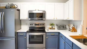 A kitchen with white cabinets, stainless steel appliances, and a wooden countertop. - The Ultimate Escape at Regal Palms w/ Pool & Lazy River (Davenport)