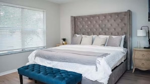 A bedroom with a large bed, a bedside table with a lamp, and a window with blinds. - The Ultimate Escape at Regal Palms w/ Pool & Lazy River (Davenport)