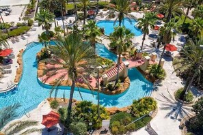 Ein Resort mit einem zentralen Pool, Palmen und Liegestühlen.