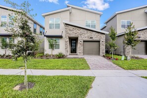 A modern two-story residential building with a stone facade, a garage, and a well-maintained lawn. - All-new, Charming Home With Screened Pool With Spa, Game Room, & Foosball (Davenport)
