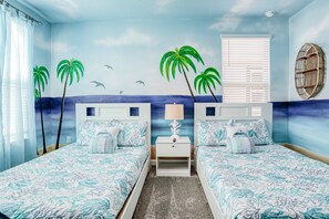 A room with two beds, a nightstand, a window with blinds, and a wall mural of palm trees and a beach. - All-new, Charming Home With Screened Pool With Spa, Game Room, & Foosball (Davenport)