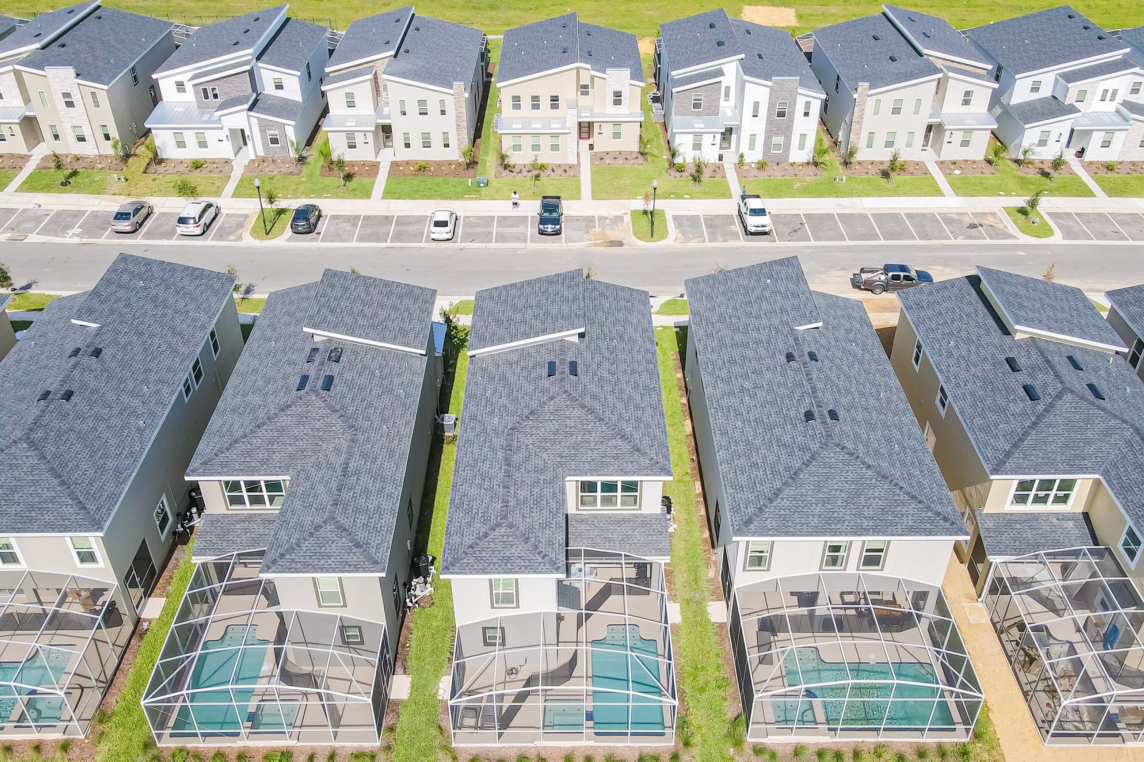Un quartiere residenziale con diverse case a due piani, una piscina e un parcheggio.