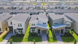 A residential area with modern houses, a central driveway, and a small park. - All-new, Charming Home With Screened Pool With Spa, Game Room, & Foosball (Davenport)