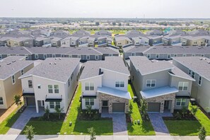 A residential area with modern houses, a central driveway, and a small park. - All-new, Charming Home With Screened Pool With Spa, Game Room, & Foosball (Davenport)