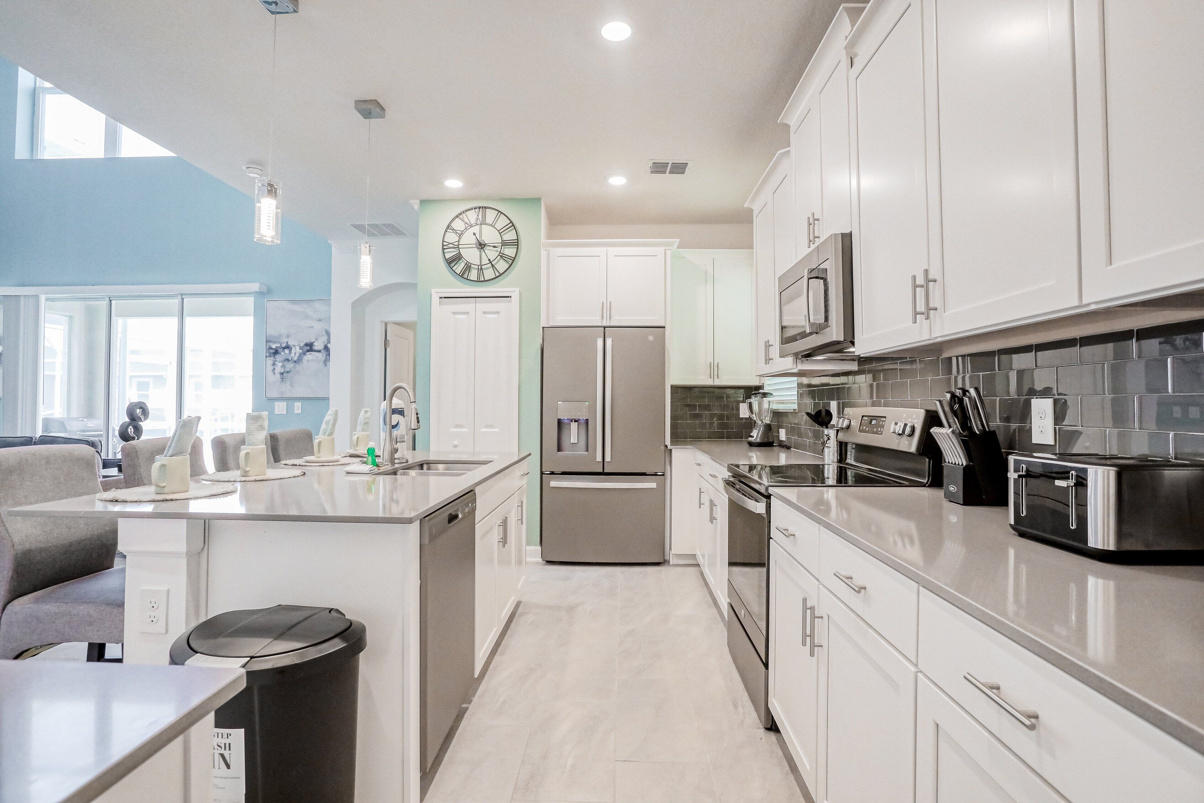 Una cocina moderna con electrodomésticos de acero inoxidable, armarios blancos y una isla grande con asientos.
