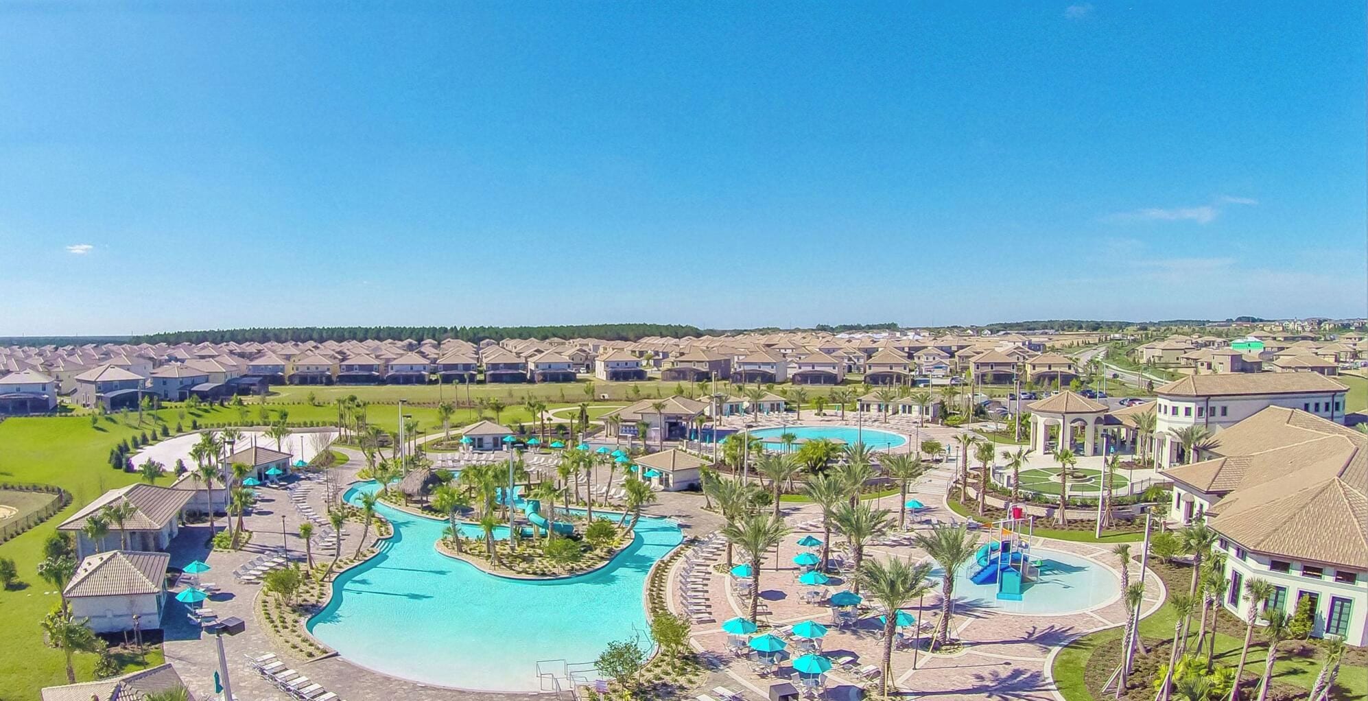 A resort with multiple swimming pools, lounge areas, and a large lawn.