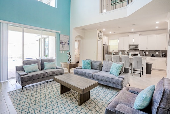A spacious living area with a large sofa set, a coffee table, and a kitchen in the background. - All-new, Charming Home With Screened Pool With Spa, Game Room, & Foosball (Davenport)