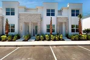 Ein modernes mehrgeschossiges Gebäude mit Naturstein-Fassade, einladendem Eingang und einem Parkplatz.