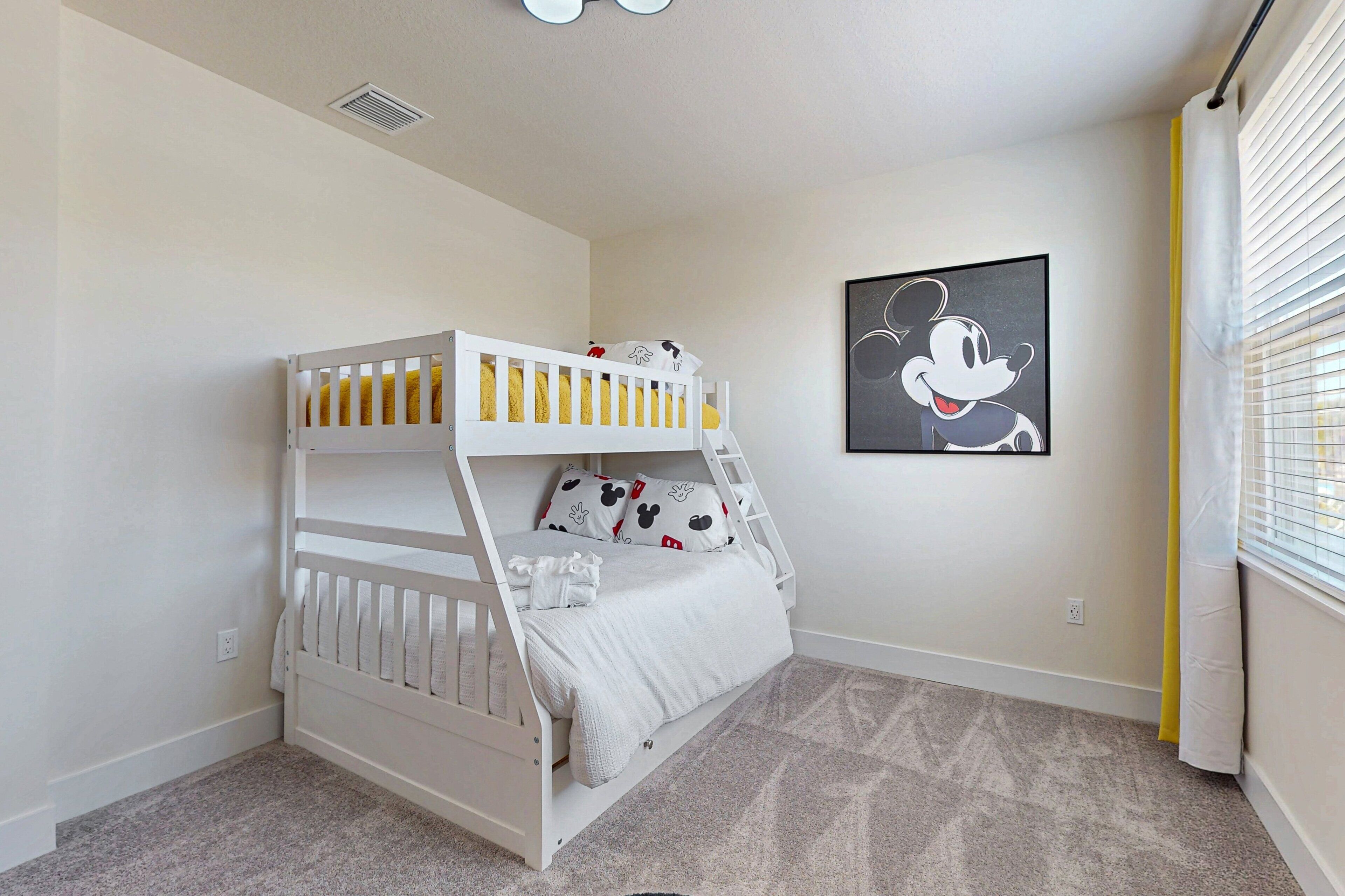 A bunk bed with a ladder, a Mickey Mouse poster, and a window with blinds.