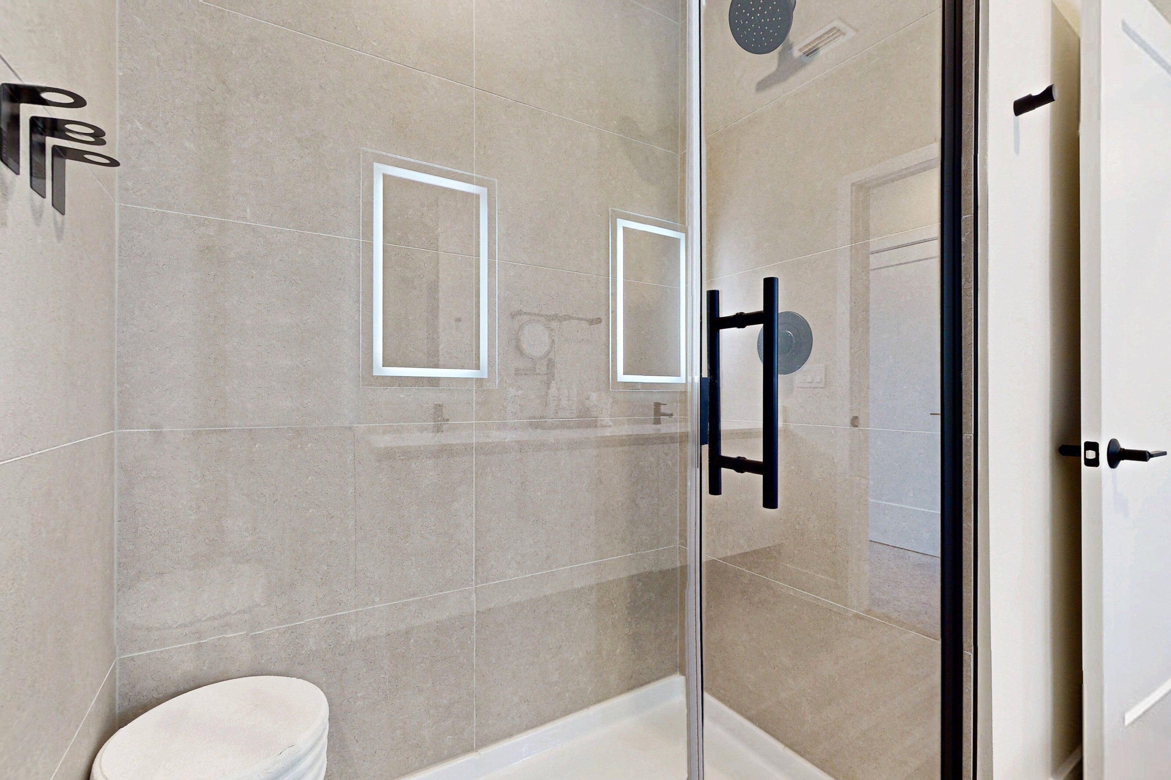A modern bathroom with a glass shower enclosure, a toilet, and a mirror.