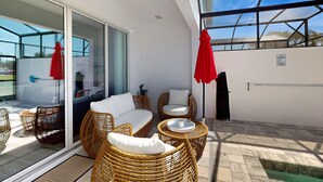 Ein Balkon mit Korbmöbeln, einer Glastür und einem roten Sonnenschirm.