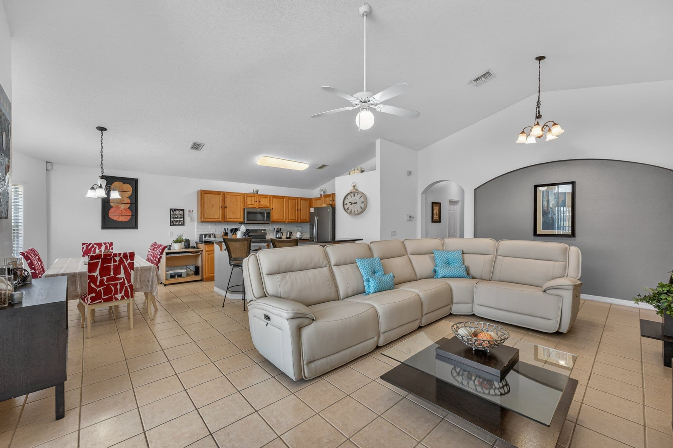 A modern living room with a sectional sofa, a dining area, and a kitchen in the background.