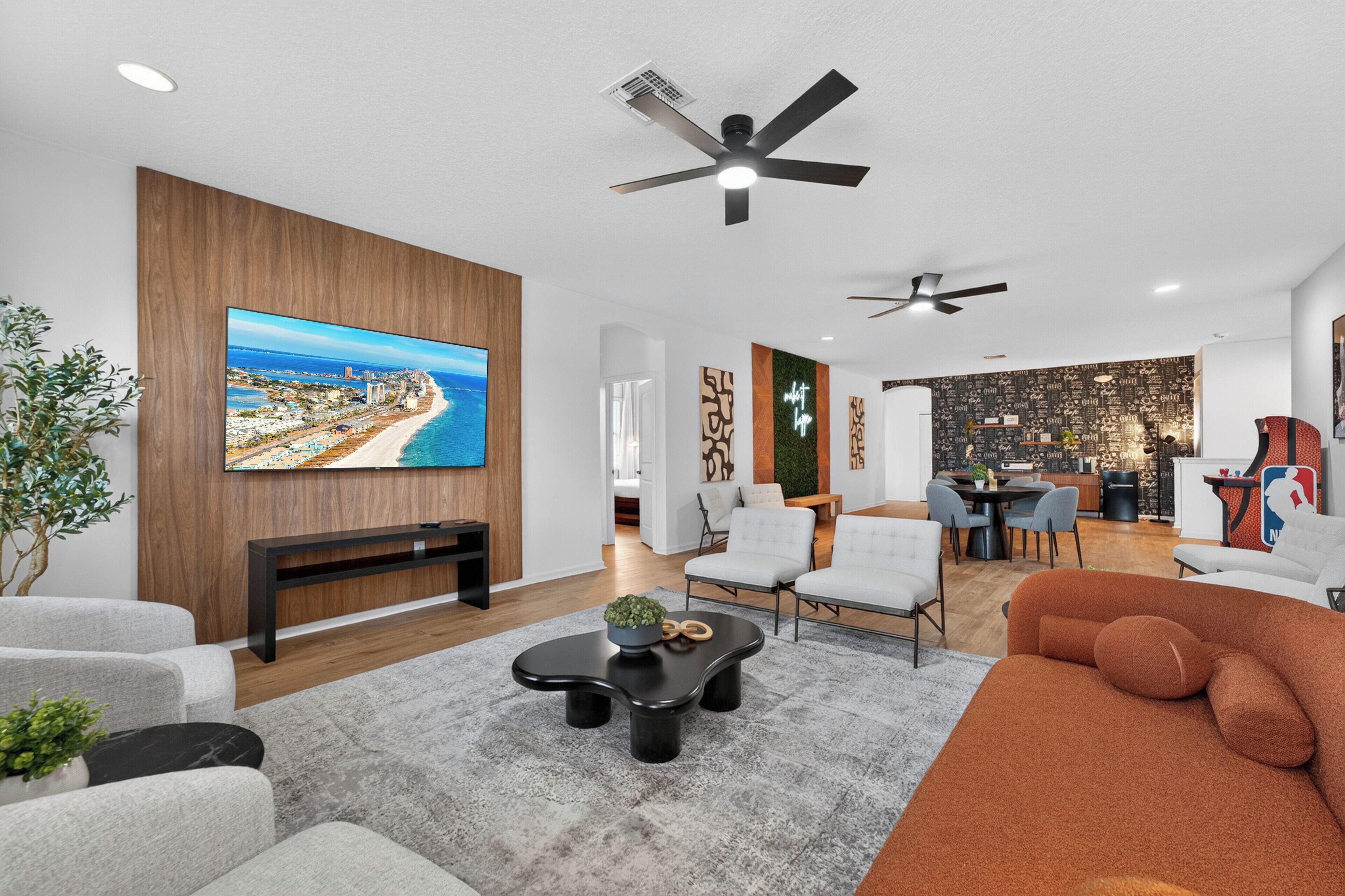 Ein modernes Wohnzimmer mit großem Fernseher, Sitzgelegenheiten und einem Essbereich.