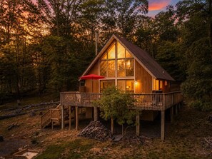 A wooden cabin with a deck, surrounded by trees. - Timber Ridge Cabin - Wifi | Fire pit | Horseshoe Pit | Outdoor Shower | Deck | Games (Berkeley Springs)