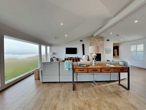 Uma sala de estar espaçosa com uma grande janela, uma lareira e uma televisão de tela plana.