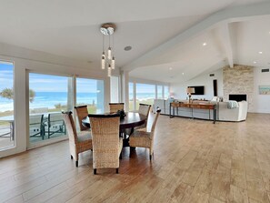 A spacious dining area with a view of the ocean, a kitchen with a stone wall, and a living area with a fireplace. - Ocean Sunrise (Ponte Vedra Beach)