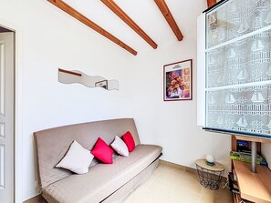 Een kamer met een bank, een lijst met kunstwerk en een decoratief object aan de muur.