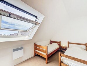 Quarto com claraboia, cama, mesa de cabeceira e aquecedor.