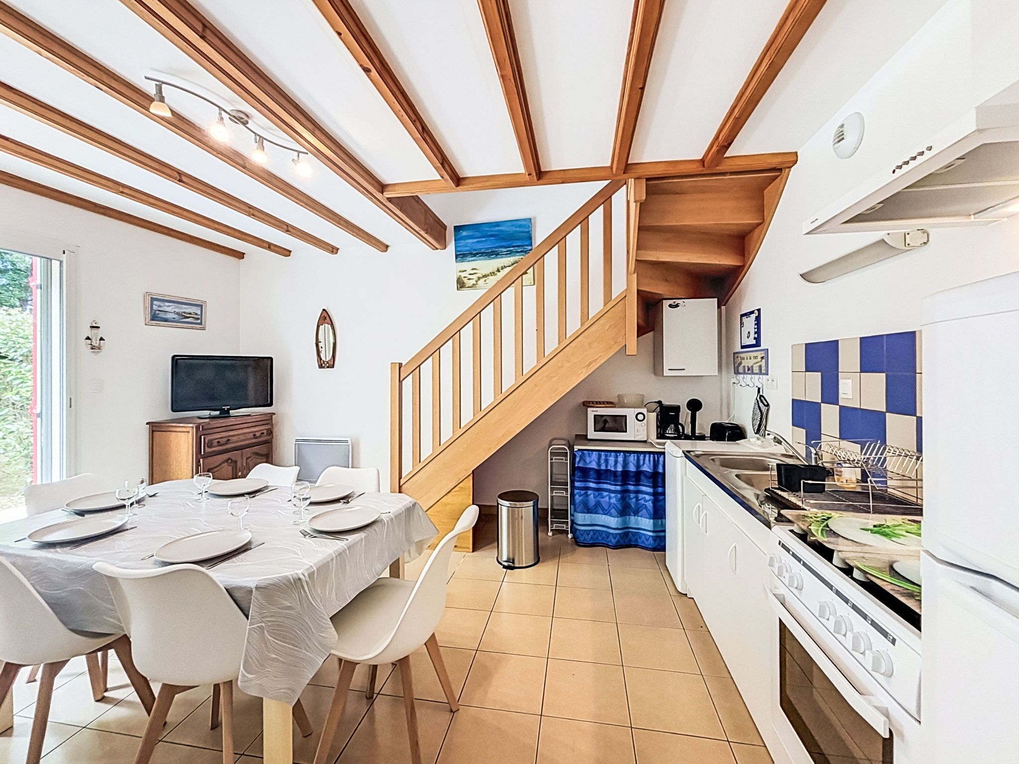 Una cocina compacta con zona de comedor, vigas de madera, microondas y estufa.