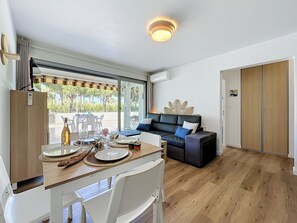 Een moderne woonkamer met een eethoek, een bank, een houten kast en uitzicht door een glazen deur.