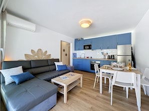 Ein modernes Wohnzimmer mit Sofa, Couchtisch und Essbereich mit Stühlen und Tisch.