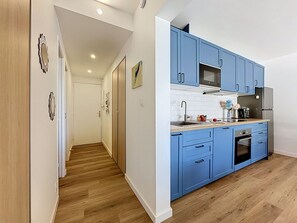 Een moderne keuken met blauwe kastjes, een magnetron, een koelkast en een spoelbak.