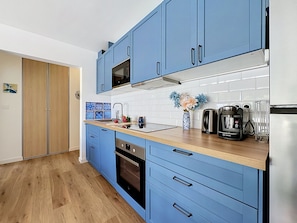 Eine moderne Küche mit blauen Schränken, einem Edelstahl-Kühlschrank, einer Kaffeemaschine und einer Mikrowelle.