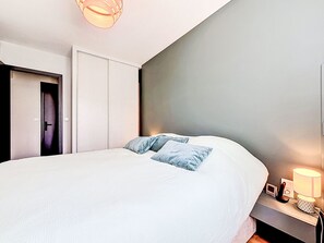 Ein Schlafzimmer mit Bett, Nachttisch, Lampe und Kleiderschrank.