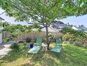 A backyard with two green chairs, a tree, and a wooden fence. - Maison de Suffren by Interhome (St Gildas-de-Rhuys)