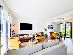 A modern living room with a sofa, armchairs, a coffee table, a TV, and a dining area with a table and chairs. - Maison de Suffren by Interhome (St Gildas-de-Rhuys)