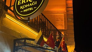 A hotel sign with flags, a balcony, and a staircase. - Erkar Konağı (Mardin)