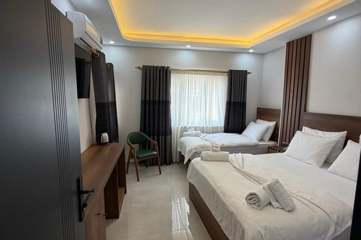 Habitación de hotel con dos camas, un escritorio, una silla y un televisor.