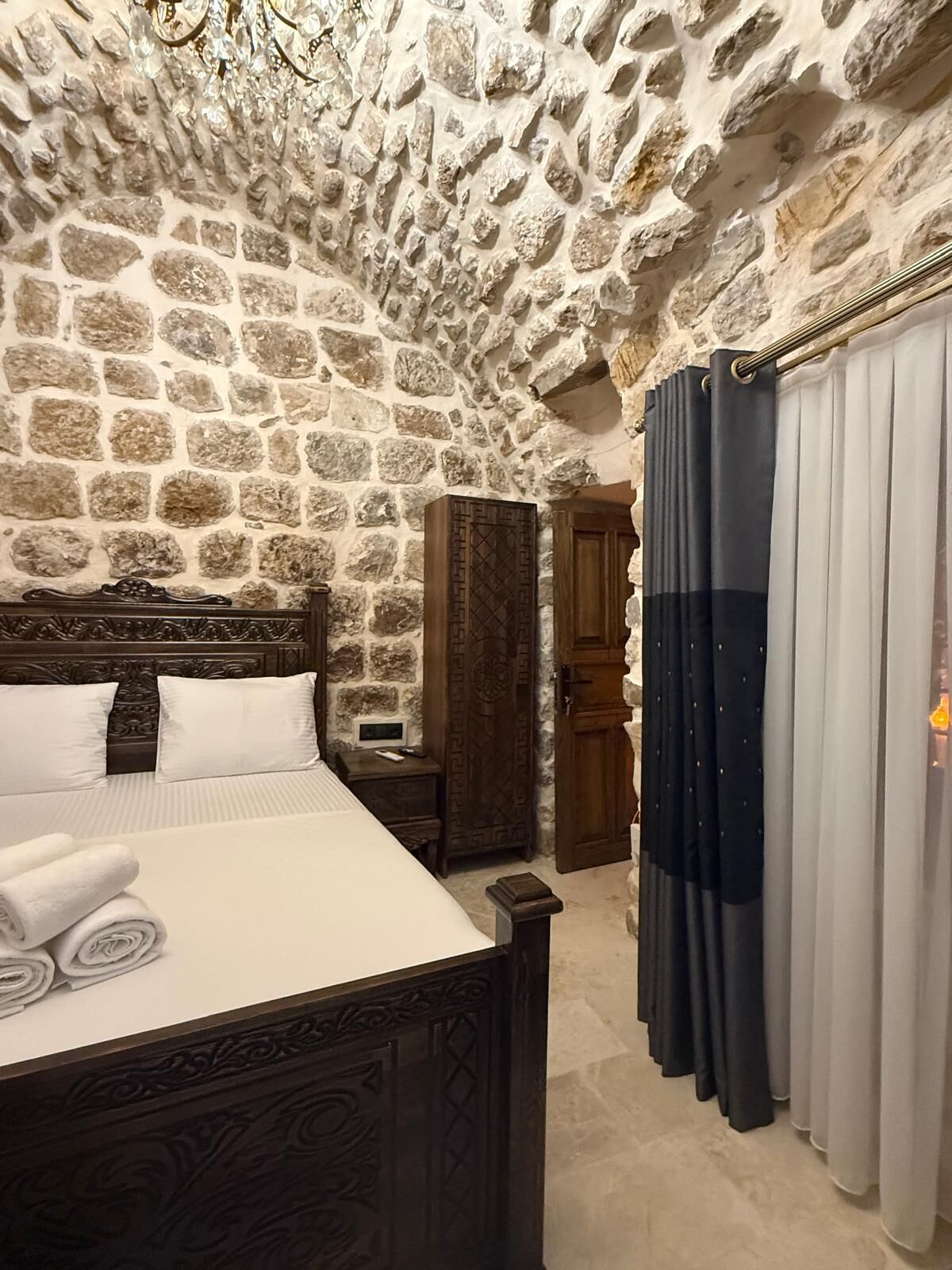 Camera da letto con pareti in pietra, un letto, un armadio e una porta.