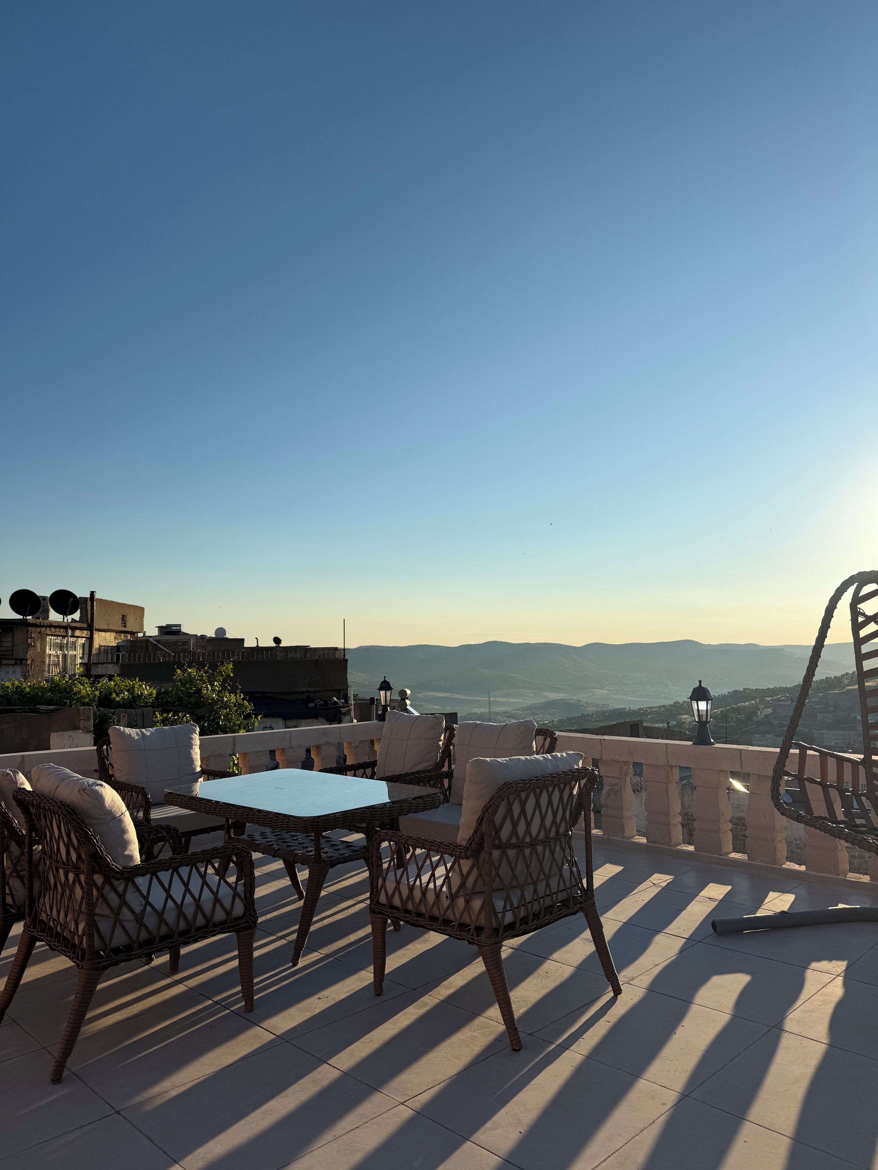 Un espace extérieur aménagé avec des meubles en osier et une table, offrant une vue sur un paysage pittoresque.
