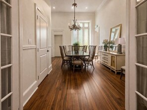 A dining area with a wooden table and chairs, a chandelier, and a cabinet with a mirror. - Luxury Queen Studio - Solara at The Marle Boutique Hotel-Near JHU + Downtown (Baltimore)