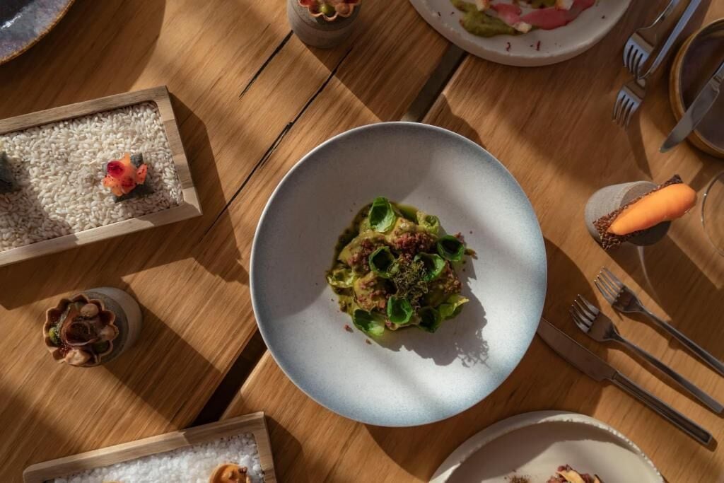 A dining table with a plate of food, a small bowl, and a few scattered items.